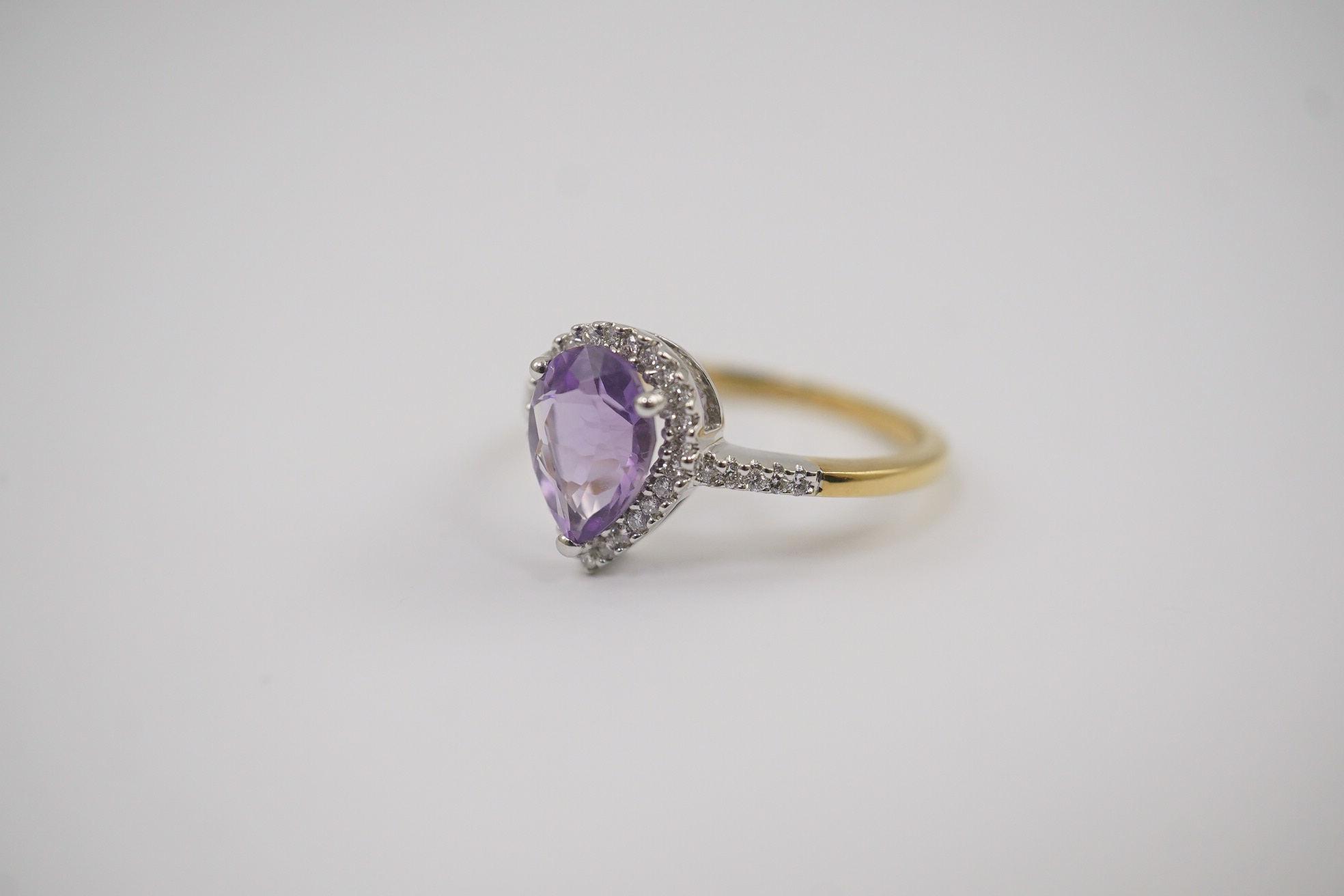 A modern 18ct gold and single stone pear cut amethyst set ring, with diamond chip set border and shoulders